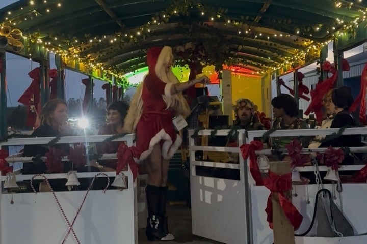 People in festive attire on a decorated boat with holiday lights.